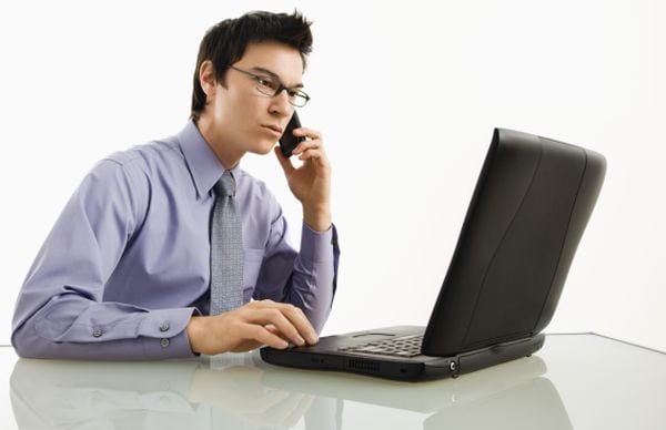 Businessman on laptop and cell phone.